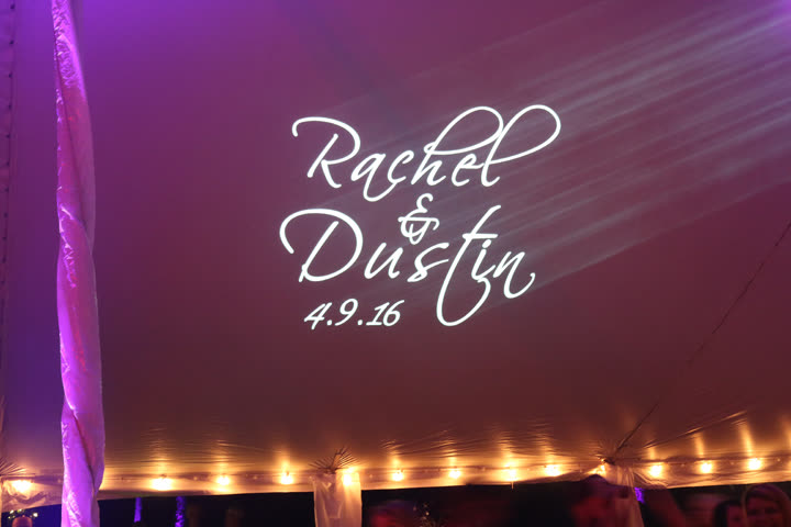 Custom monogram lighting projected on a wedding reception tent ceiling